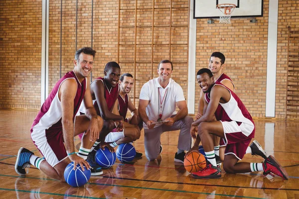 Coach and players kneeling with basketball