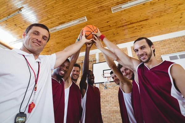 Jogadores e treinador segurando basquete juntos — Fotografia de Stock