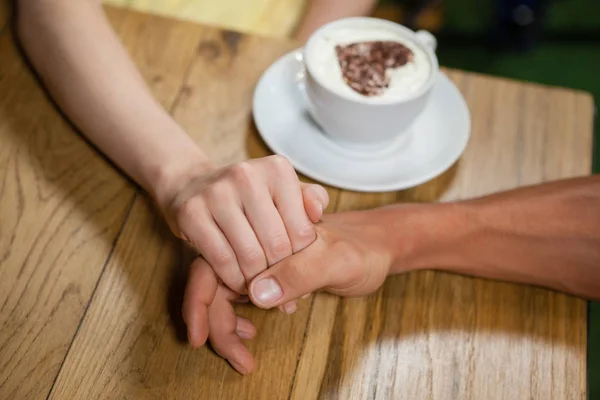 Casal de mãos dadas por copo de café — Fotografia de Stock