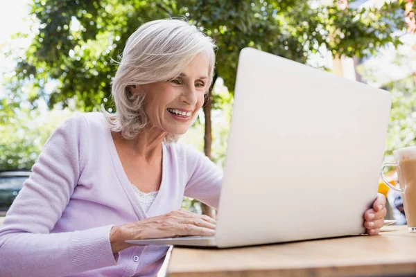 Senior kobieta korzysta z laptopa w kawiarni na świeżym powietrzu — Zdjęcie stockowe