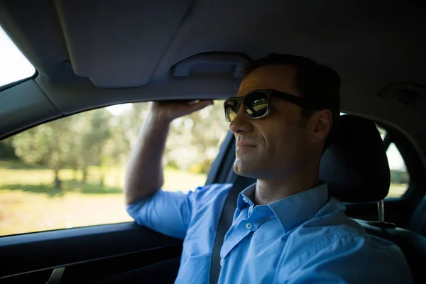 Hombre usando gafas de sol en el coche — Foto de Stock