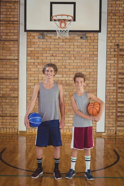 Escola meninos segurando basquete no tribunal — Fotografia de Stock