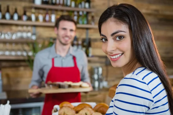 Kvinna med servitören stående i bakgrunden — Stockfoto