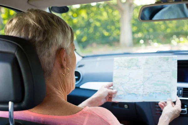 Mujer mayor leyendo mapa mientras está en el coche — Foto de Stock