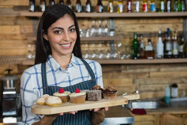 Garçonete segurando cupcakes na bandeja — Fotografia de Stock