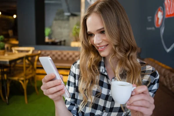 Kobieta przy użyciu telefon trzymając kubek kawy — Zdjęcie stockowe