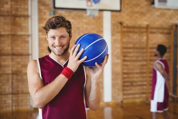 Jogador de basquete segurando basquete na quadra — Fotografia de Stock