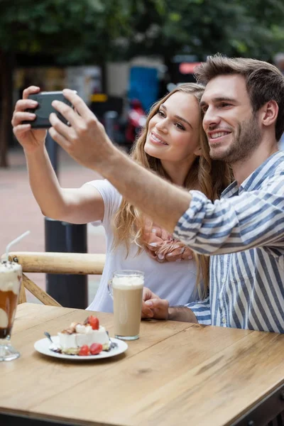 Пара держит смартфон на тротуаре кафе — стоковое фото