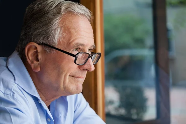 Un uomo anziano sorridente che guarda altrove — Foto Stock