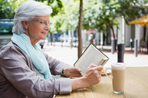 Oudere vrouw die een boek leest — Stockfoto