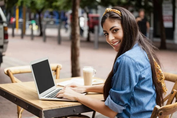Mulher usando laptop enquanto sentado no café da calçada — Fotografia de Stock