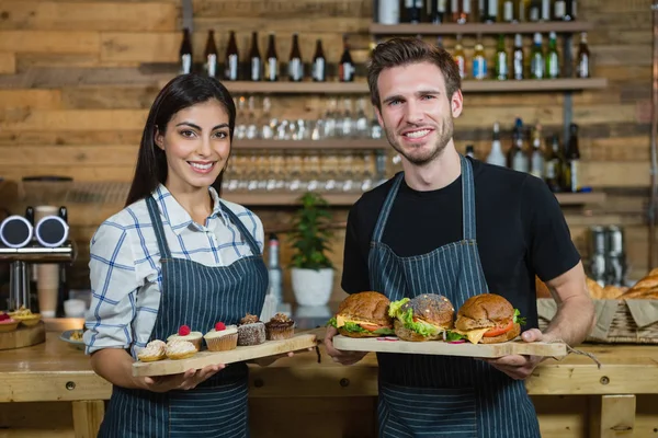 Camarero y camarera sosteniendo cupcakes y comida — Foto de Stock