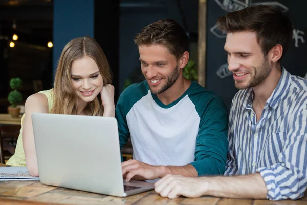 Friends looking at laptop while sitting on chair — Stock Photo, Image