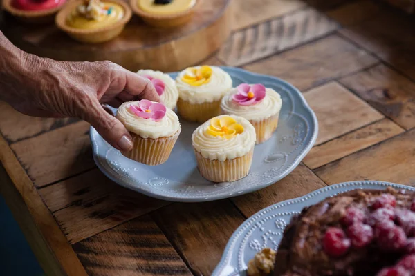 Mujer mayor sosteniendo cupcake en la mesa — Foto de Stock