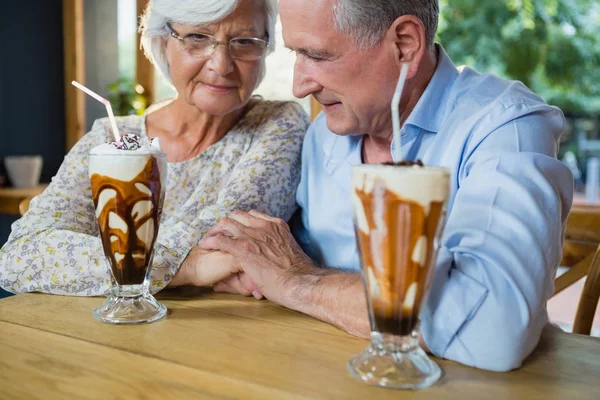 Senior couple holding hands while having coffee — Stock Photo, Image