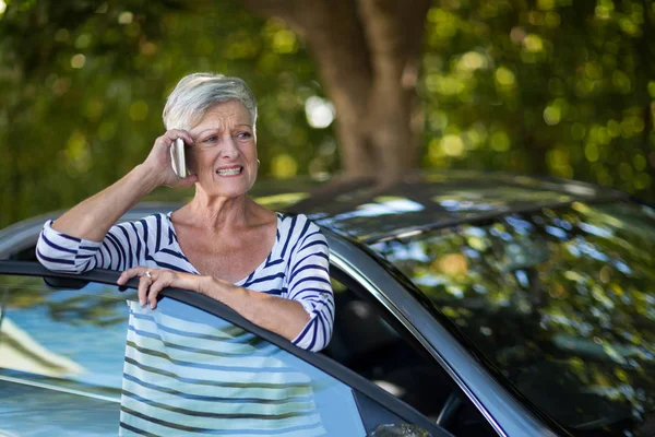 Senior woman talking on phone by car — Stock Photo, Image