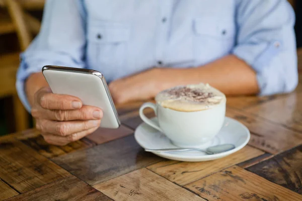 커피 컵에 의해 스마트폰 들고 사람 — 스톡 사진