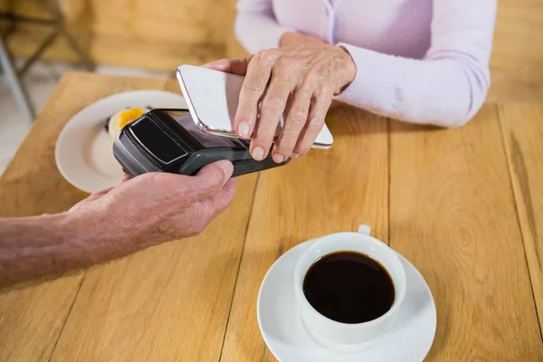 Mulher fazendo pagamento através da tecnologia NFC — Fotografia de Stock