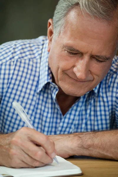 Senior man schrijven op dagboek — Stockfoto