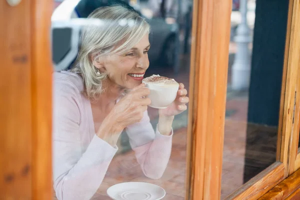 Senior mujer bebiendo café mientras por mesa — Foto de Stock