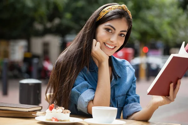 Mulher ler livro enquanto sentado na cadeira no café — Fotografia de Stock