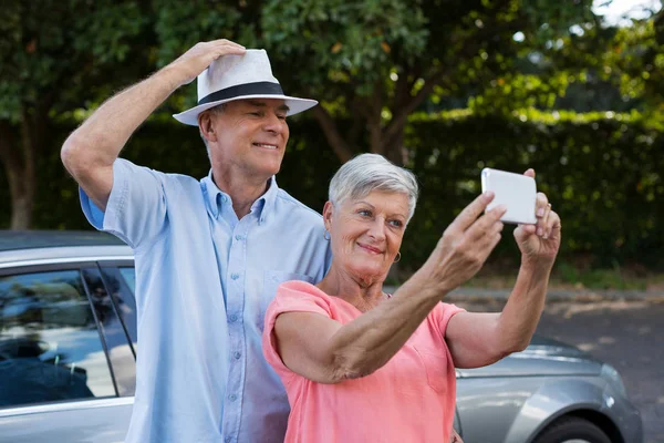 Senior woman taking selfie with man by car — Stock Photo, Image