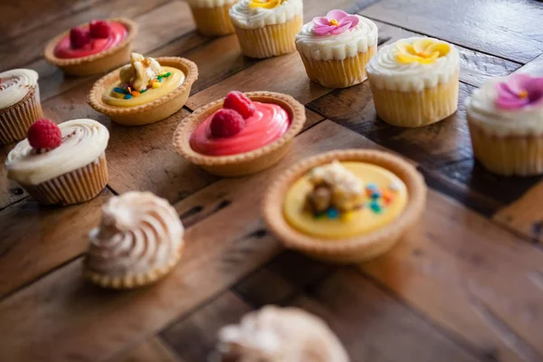 Tarta y cupcakes arreglados en la mesa —  Fotos de Stock