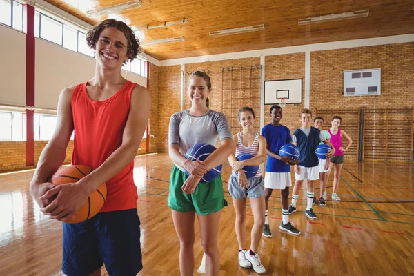 Equipe do ensino médio segurando basquete na corte — Fotografia de Stock