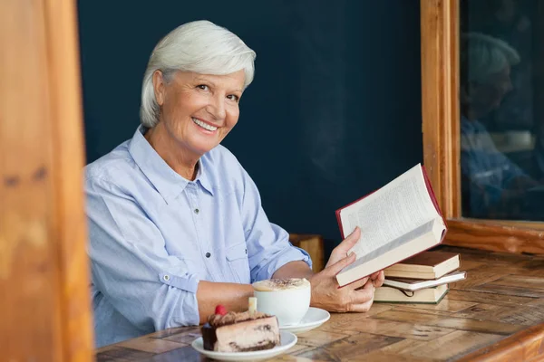 Lachende senior vrouw met boek — Stockfoto