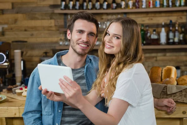 Casal sorrindo usando tablet digital no balcão — Fotografia de Stock