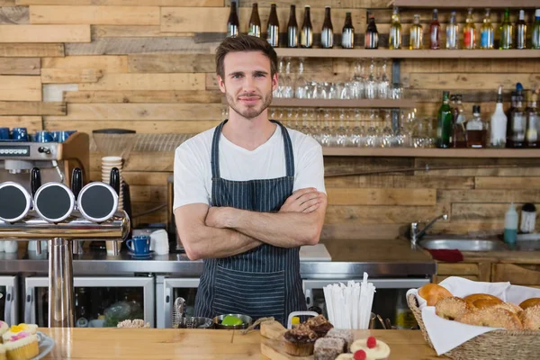 Servitören som står med armarna korsade vid counter — Stockfoto
