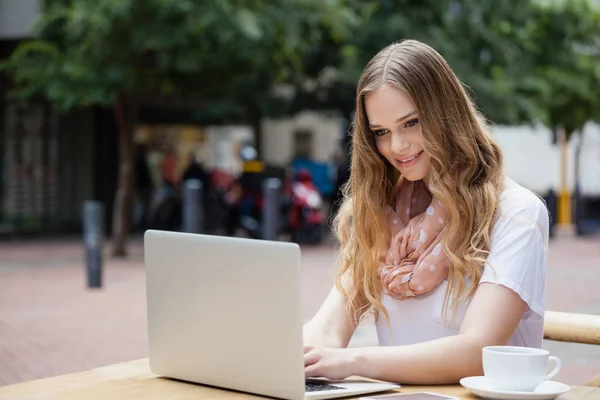 Mulher usando laptop digital enquanto se senta à mesa — Fotografia de Stock