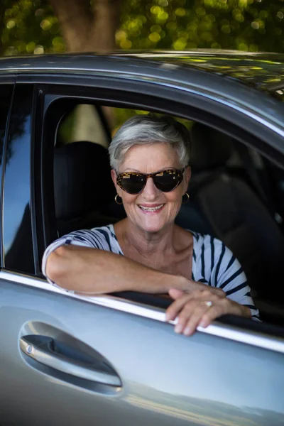 Smiling senior woman sitting in car — Stock Photo, Image