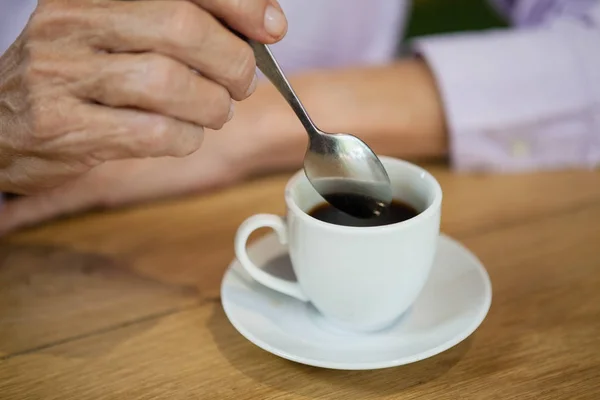 Senior Kvinna omrörning kaffe — Stockfoto