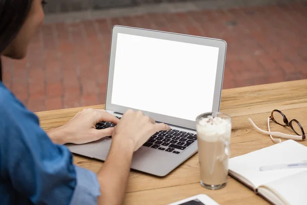 Žena pomocí laptopu, zatímco u stolu — Stock fotografie