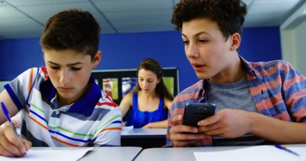 Student med mobiltelefon i klassrummet — Stockvideo