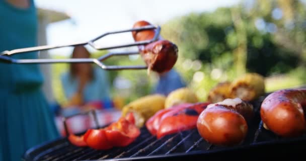 Mädchen wirft Würstchen auf Grill — Stockvideo