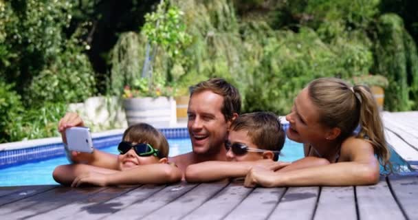 Familia feliz usando teléfono móvil cerca de la piscina — Vídeo de stock