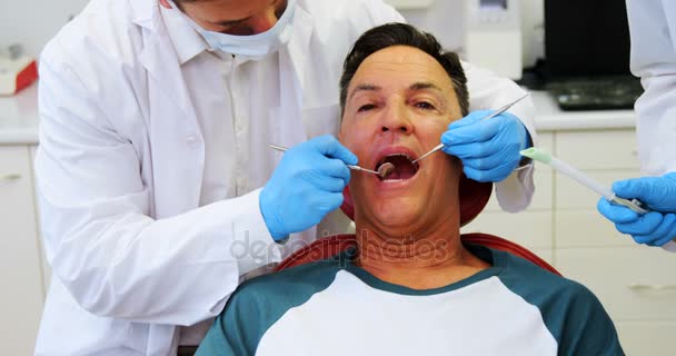 Dentistas examinando um paciente do sexo masculino com ferramentas — Vídeo de Stock