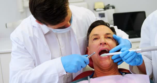 Стоматологи осматривают пациента с помощью инструментов — стоковое видео