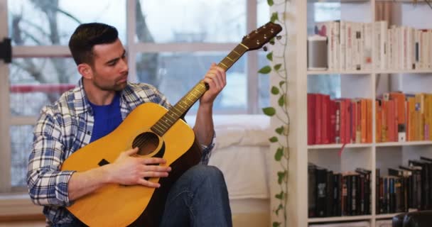 Hombre tocando la guitarra en la sala de estar en casa — Vídeos de Stock