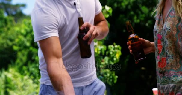 Groep vrienden met een flesje bier tijdens de voorbereidingen van de barbeque — Stockvideo