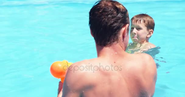 Família feliz fazendo batalha arma de água na piscina — Vídeo de Stock