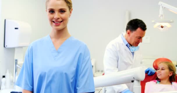 Uśmiechający się asystent dentystyczny, stojąc w klinice stomatologicznej — Wideo stockowe