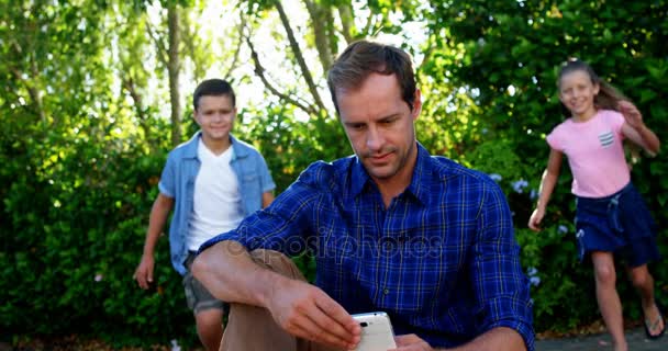Діти грають зі своїм батьком у парку — стокове відео