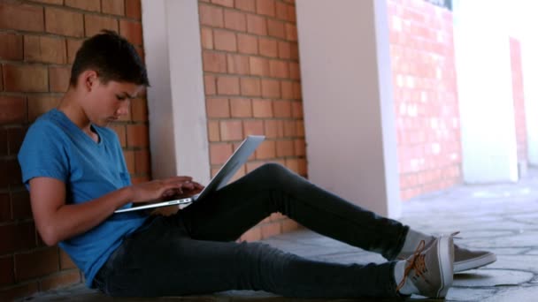 Schooljongen zitten in gang en het gebruik van laptop — Stockvideo