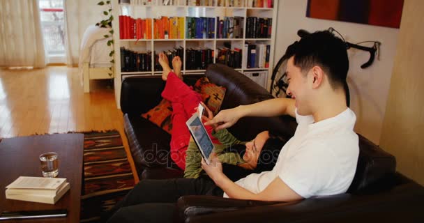 Çift dijital tablet ve cep telefonu kullanarak oturma odasında kanepede rahatlatıcı — Stok video