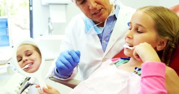 Dentist assisting young patient while brushing teeth — Stock Video