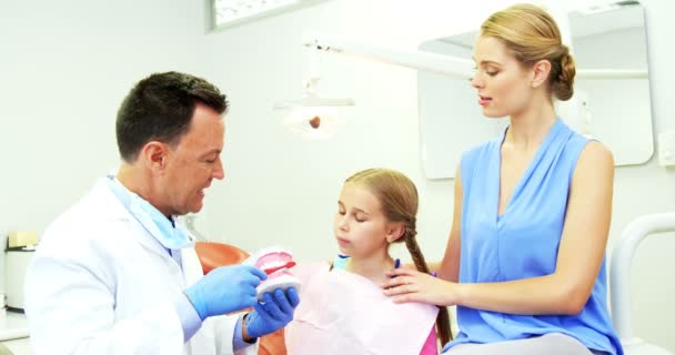 若い患者の歯を磨く方法を示す歯科医 — ストック動画