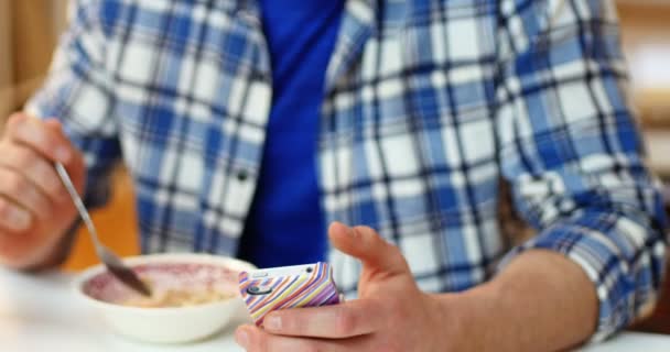 Hombre usando el teléfono móvil mientras desayuna — Vídeos de Stock